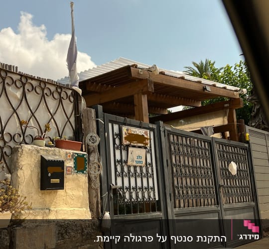שער מתכת עם גג עץ בחצר